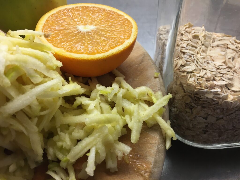 sliced orange and grated apples with oats nicely displayed on a wooden board