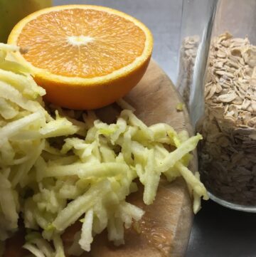 sliced orange and grated apples with oats nicely displayed on a wooden board