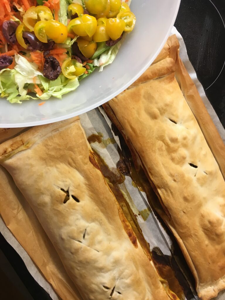 two curry puffs bakes on display with a side salad 